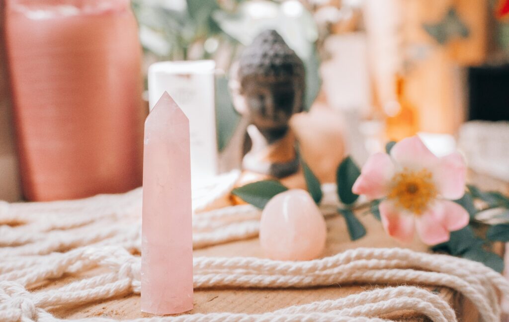 A tranquil setup featuring rose quartz with a Buddha statue and flower accents.